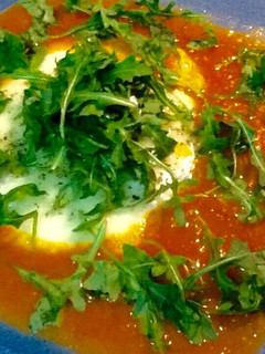 Una foto de Queso provolone con salsa de tomate y rúcula