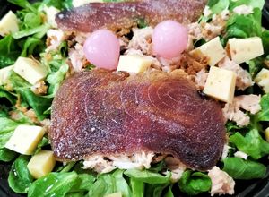 Una foto de Ensalada de canónigos con atún, mojama y queso de tomates secos con aceitunas negras