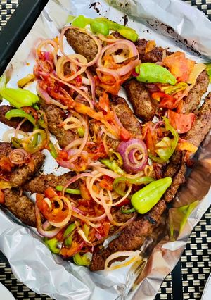 A picture of Baked Seekh kabab with tomatoes.