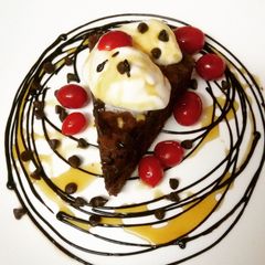 A picture of Chocolate brownie served with vanilla ice cream and maple syrup.