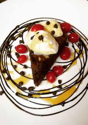 A picture of Chocolate brownie served with vanilla ice cream and maple syrup.