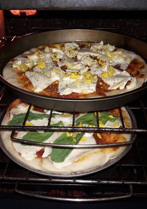 Una foto de Pizza casera con huevo y rúcula
