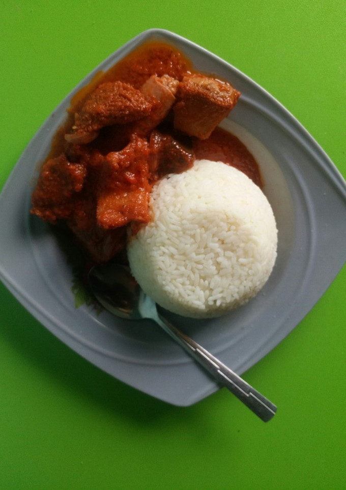 A picture of Rice and stew with assorted meat.