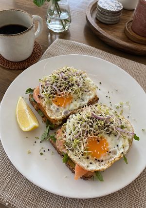 A picture of Smoked Salmon & Egg Toast with Arugula and Sprouts.