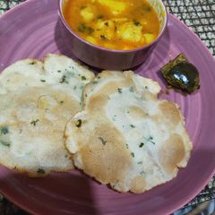 A picture of Aloo sabzi with rice Puri.