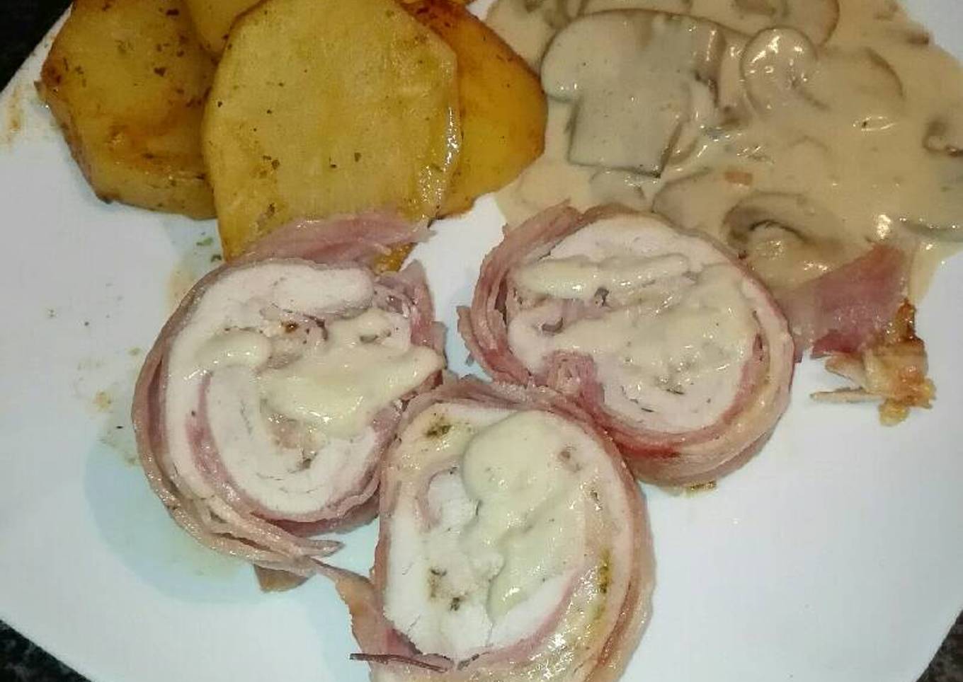 Rollo de pechuga envuelto en beicon y relleno de jamón York y queso con salsa de champiñones y almendras