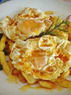 Una foto de Huevos fritos con patatas, ajos enteros y pimientos de padrón