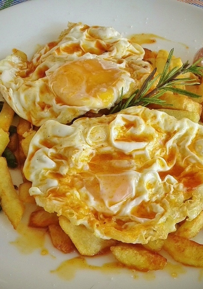 Una foto de Huevos fritos con patatas, ajos enteros y pimientos de padrón