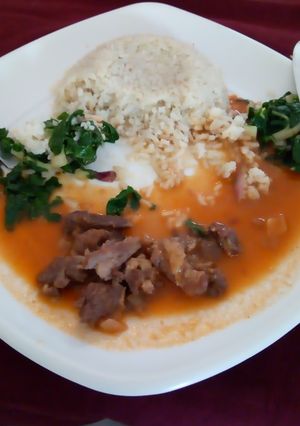 A picture of Rice pillaf with beef stew and saute spinach.