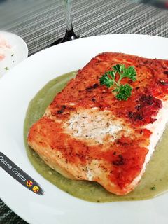 Una foto de Salmón dorado sobre salsa de perejil 🌿✨