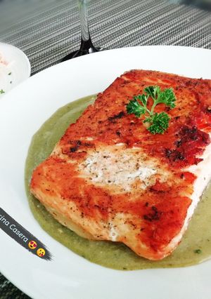 Una foto de Salmón dorado sobre salsa de perejil 🌿✨