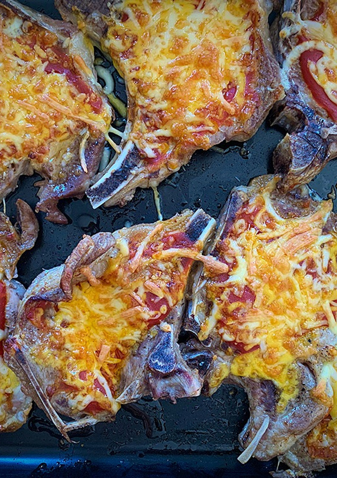 Una foto de Chuletas, tomate y queso gratinado