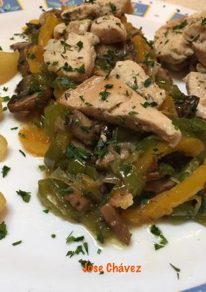 Una foto de Pechuga pollo sobre cama de pimientos, cebolla y champiñones