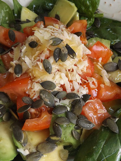 Una foto de Ensalada simple de hojas de espinacas crudas con aguacate, pepino y tomates