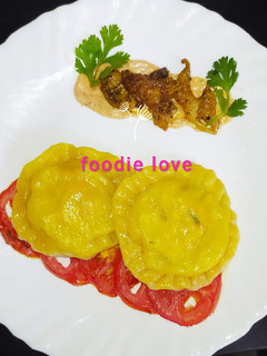 A picture of Carrot infused chicken ricotta ravioli with baked tomato sauce.