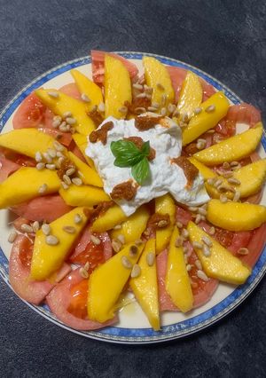 Una foto de Ensalada de tomate y mango con piñones,burrata y pesto