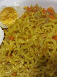 A picture of Curry noddles with carrots and boiled egg.