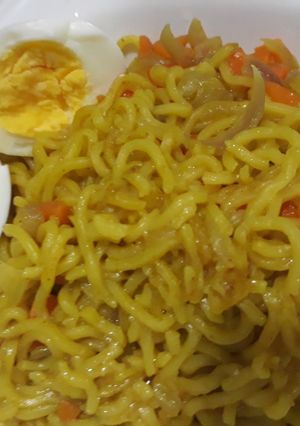 A picture of Curry noddles with carrots and boiled egg.