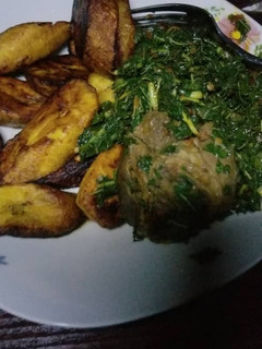 A picture of Plantain with Vegetable sauce and goat meat.