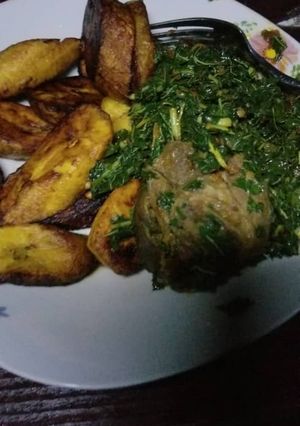 A picture of Plantain with Vegetable sauce and goat meat.