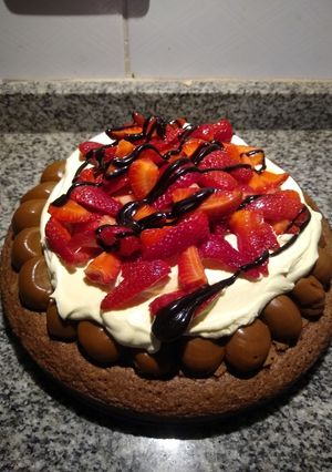Una foto de Brownie con dulce de leche, crema y frutillas