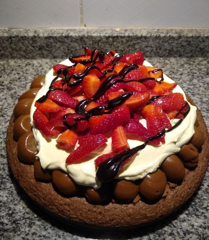 Una foto de Brownie con dulce de leche, crema y frutillas