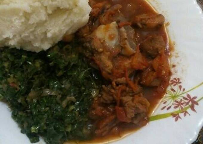 Fried Goat meat served with greens and ugali