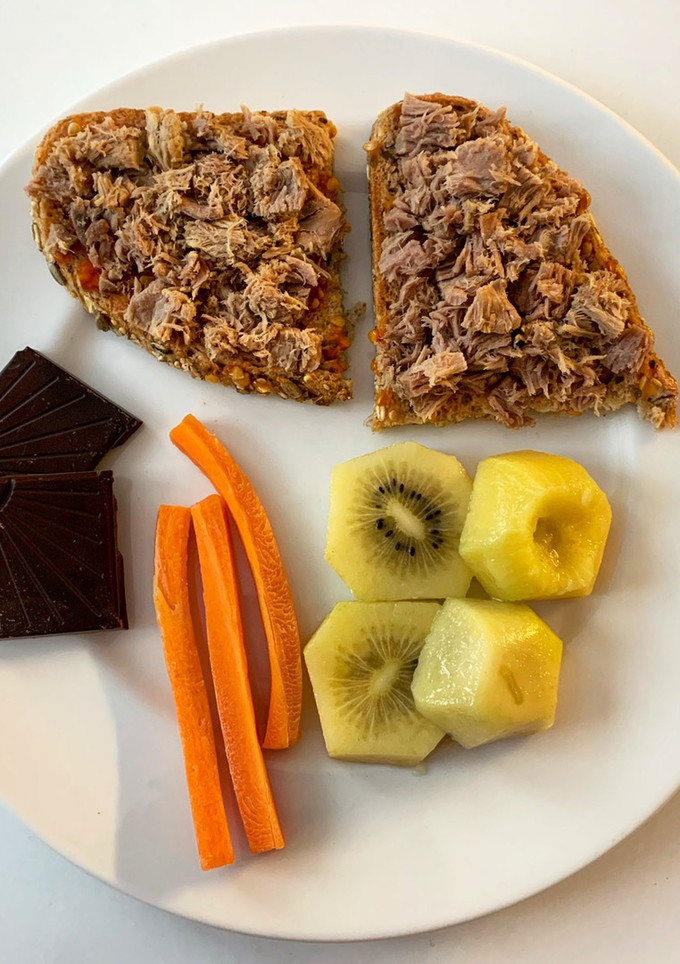 Una foto de Tostada con atún y tomate, con kiwi, zanahoria y chocolate
