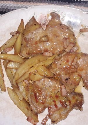 Una foto de Chuletitas de cerdo con panceta ahumada y papas fritas