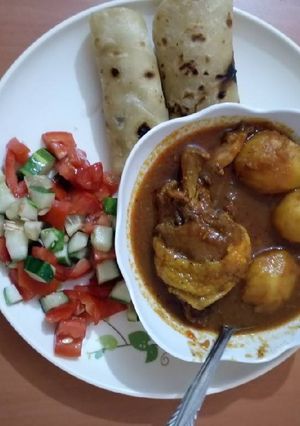 A picture of Chicken potato stew with chapati and tomato cucumber salad.
