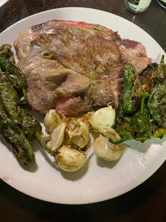 Una foto de Chuletas de aguja con ajos enteros y pimientos de Padrón semipicantes