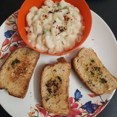 A picture of Macaroni white sauce pasta with garlic bread.