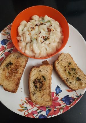 A picture of Macaroni white sauce pasta with garlic bread.