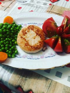 Una foto de Hamburguesa de pollo con flor de tomate, guisantes y zanahoria