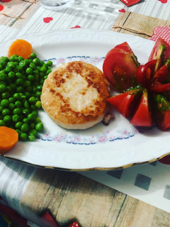 Una foto de Hamburguesa de pollo con flor de tomate, guisantes y zanahoria