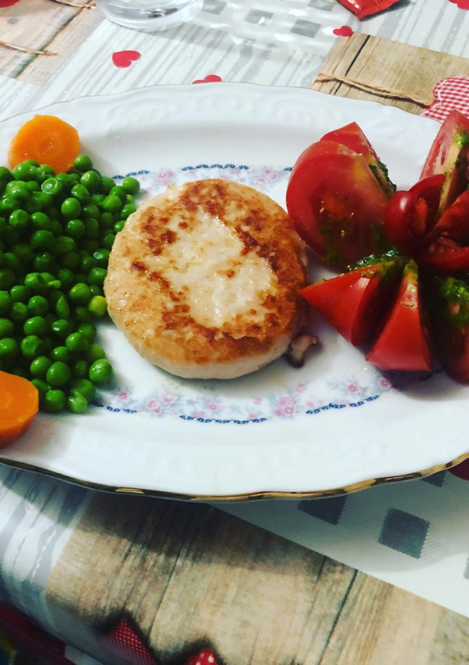 Una foto de Hamburguesa de pollo con flor de tomate, guisantes y zanahoria