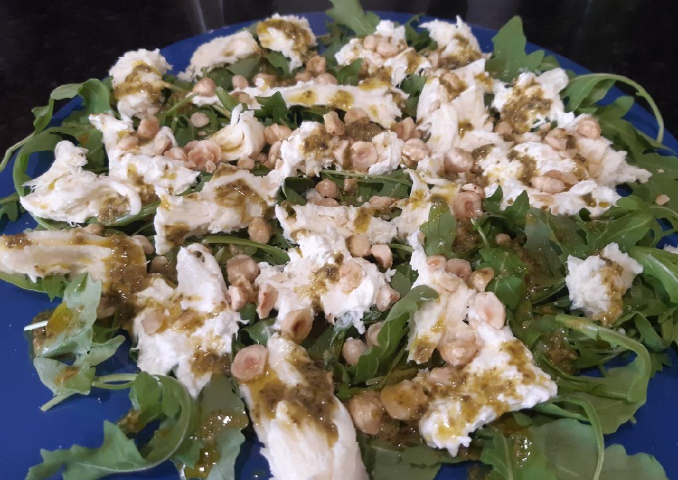 Ensalada de burrata con rúcula, pesto y avellanas
