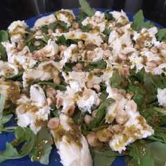 Una foto de Ensalada de burrata con rúcula, pesto y avellanas