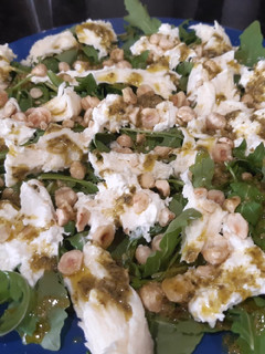 Una foto de Ensalada de burrata con rúcula, pesto y avellanas