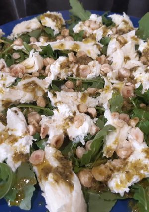 Una foto de Ensalada de burrata con rúcula, pesto y avellanas