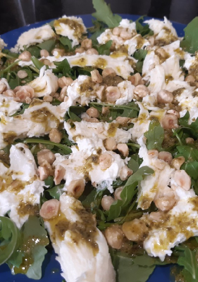 Una foto de Ensalada de burrata con rúcula, pesto y avellanas
