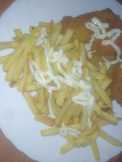 Una foto de Merluza adobada, empanada y frita con papas fritas y alioli