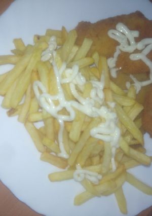 Una foto de Merluza adobada, empanada y frita con papas fritas y alioli