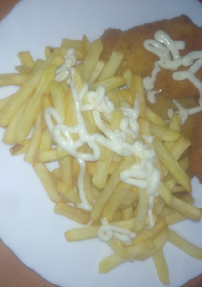 Una foto de Merluza adobada, empanada y frita con papas fritas y alioli