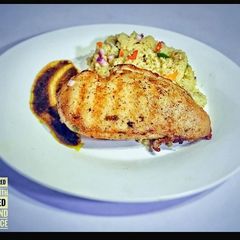A picture of Grilled chicken with Gravy Jus and buttered couscous.