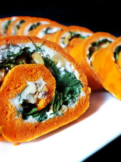 Una foto de Rollo de pimientos de piquillo relleno de rúcula, queso de cabra y nueces