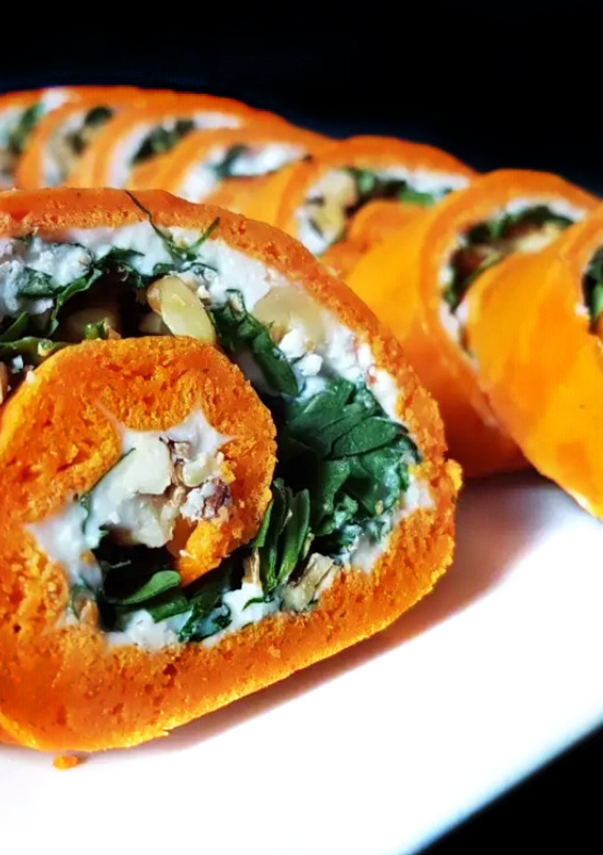 Una foto de Rollo de pimientos de piquillo relleno de rúcula, queso de cabra y nueces
