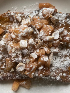 A picture of French toast, with caramelsauce, baked apple and nuts.