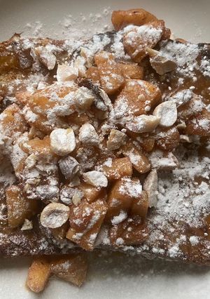 A picture of French toast, with caramelsauce, baked apple and nuts.