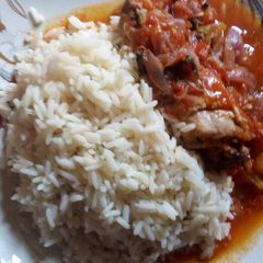 A picture of White rice and chicken sauce with curry leaf.